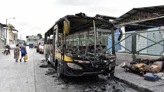 Varios ciudadanos pasan junto a los restos de un autobús incendiado en la ciudad de Guayaquil, Ecuador.