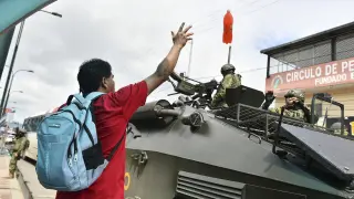 Un hombre protesta frente a una patrulla de la policía en Ecuador