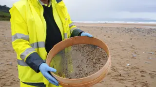 Un operario recoge pellets de plástico con un cedazo que le facilita su cribado este jueves en la playa de Vega (Asturias).