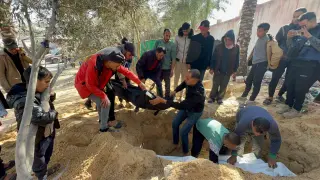 People bury bodies of Palestinians killed in an Israeli strike, at the Nasser hospital premises