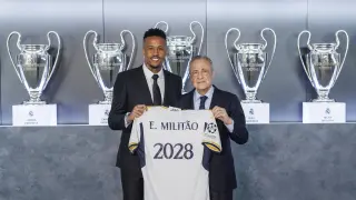El defensa brasileño Éder Militao (i) posa junto al presidente del Real Madrid, Florentino Pérez, con una camiseta con el año hasta el cual se ha extendido su contrato con el club blanco este martes, en Madrid.