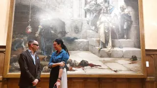 Pedro Olloqui y Lorena Orduna delante del cuadro 'La campana', en el Salón del Justicia del Ayuntamiento de Huesca.