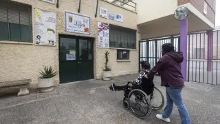 La directora del CPI La Jota entra a un alumno en silla de ruedas al colegio.