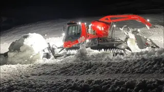 Una máquina transportando de noche nieve de fuera de pistas a la zona de La Tuca en Candanchú.
