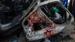 Los palestinos inspeccionan un vehículo policial que fue destruido en el campo de refugiados de Rafah, en el sur de la Franja de Gaza