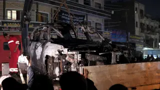 Las fuerzas de seguridad iraquíes retiran un camión quemado que fue blanco de un ataque con drones estadounidenses en el distrito de Mashtal, al este de Bagdad
