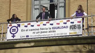 Colocación de la pancarta del 8-M en el balcón de la Subdelegación del Gobierno en Huesca.