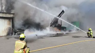 Los bomberos trabajan por apagar el fuego en una empresa de maquinaria agrícola en Fraga.