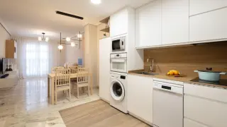 Una cocina abierta al salón que combina dos texturas en el suelo para diferenciar estancias.