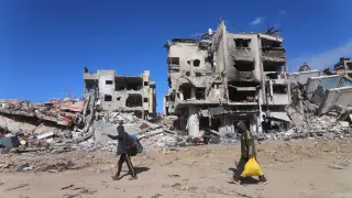 Palestinos frente a edificios destruidos por los bombardeos del Ejército de Israel contra la ciudad de Rafá, en el sur de la Franja de Gaza.