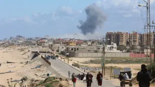 El humo se eleva tras un ataque israelí mientras los palestinos que huyen del norte de Gaza debido a la ofensiva militar de Israel se desplazan hacia el sur, en la franja central de Gaza.