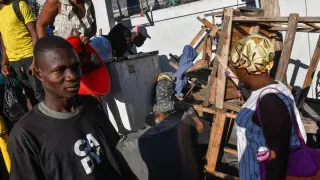 ATENCIÓN EDITORES: CONTENIDO GRÁFICO EXPLÍCITO - AME9715. PUERTO PRÍNCIPE (HAITÍ), 18/03/2024.- Varias personas observan el cadáver de una persona en el suelo este lunes, en Puerto Príncipe (Haití). Doce cadáveres fueron encontrados este lunes en Petion-Ville, en las colinas de Puerto Príncipe, en circunstancias aún por aclarar, como la identidad de las víctimas, que no se descarta sean miembros de bandas armadas abatidos por la Policía Nacional. Los cuerpos, entre ellos el de una mujer, fueron hallados dispersos en plena vía, en los alrededores de una zona dedicada al comercio informal de alimentos y otros productos. EFE/ Johnson Sabin
