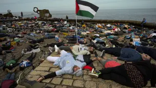 Miles de personas tumbadas junto al Peine de los Vientos en protesta por la guerra en Gaza