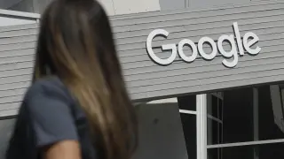 Una mujer camina bajo un cartel de Google en el campus en Mountain View,