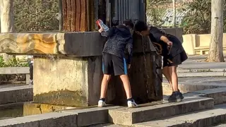 Dos jóvenes calman su sed en la fuente de Torán de Teruel.