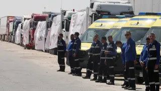Ambulancias y camiones con ayuda humanitaria esperan junto a a frontera entre Egipto y Gaza