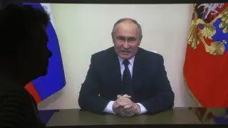 Una mujer sigue el discurso de Putin por televisión