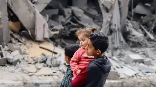 Tres niños deambulan solos en medio de la desolación tras el bombardeo de su casa en el sur de Gaza.
