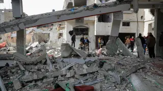 Palestinos entre los restos de edificios destruidos por los bombardeos del Ejército de Israel contra la ciudad de Rafá, en el sur de la Franja de Gaza.