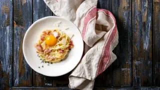 Plato de pasta carbonara con los ingredientes originales: huevo, queso y guanciale.