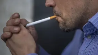 Un hombre enciende un cigarro