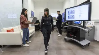 Irene Bosque y Pablo Pérez Lázaro observan los datos que ofrece el traje que lleva Pilar Salvo, en el Laboratorio de Inteligencia Artificial del ITA, en Zaragoza.