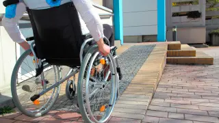 Una mujer asciende por una rampa con su silla de ruedas.