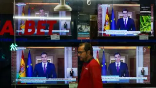 A person walks next to TVs broadcasting the statement by Spains Prime Minister Pedro Sanchez, in El Masnou, north of Barcelona, Spain April 29, 2024. REUTERS/Albert Gea [[[REUTERS VOCENTO]]]
