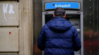 Foto de archivo de un cliente del Sabadell sacando dinero de un cajero