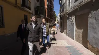 Un vecino enseña una casa tapiada al vicepresidente aragonés, Alejandro Nolasco, en su visita al sector Zamoray-Pignatelli de Zaragoza, uno de los más afectados por ocupaciones de pisos.