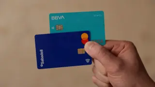 A man shows his debit cards of BBVA and Sabadell banks, in Ronda