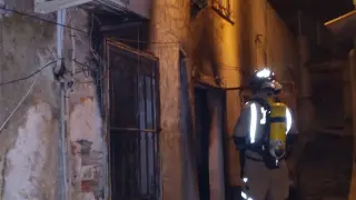 Los bomberos a la entrada de la vivienda incendiada.