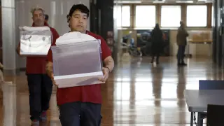 Dos operarios municipales transportan urnas en el colegio electoral situado en el edificio Novíssim del Ayuntamiento de Barcelona