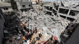 Palestinians inspect the site of an Israeli strike on a house, in Nuseirat