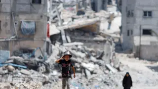 Palestinos destrozan entre edificios destruidos tras el último ataque del ejército israelí.