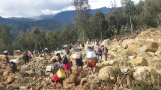 Personas cargando bolsas después de un deslizamiento de tierra en la provincia de Enga, Papúa Nueva Guinea
