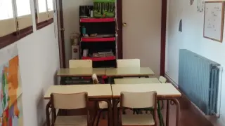 Mesas y sillas colocadas en el pasillo de colegio de Gea de Albarracín para impartir una clase.