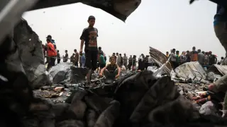 Palestinos inspeccionan los restos del campo de desplazados tras el ataque israelí la madrugada del lunes.