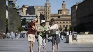 Tres turistas este martes consultando un mapa en la plaza del Pilar de Zaragoza.