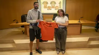 El segundo entrenador del Pamesa, Maxi Torcello, y la diseñadora de la nueva equipación, Sara Brezaeru, posan con la camiseta antigua y, de fondo, la nueva indumentaria.