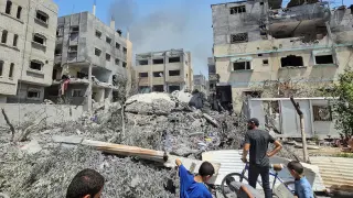 Palestinians inspect a house hit in an Israeli strike, due to an Israeli military operation, in Nuseirat refugee camp