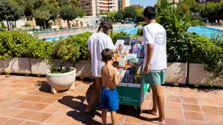 Unos niños miran los libros en una de la piscinas públicas de Zaragoza.