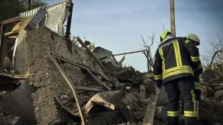 Rescatistas ucranianos trabajando en el lugar de un ataque con cohetes contra una aldea cerca de Kiev, Ucrania