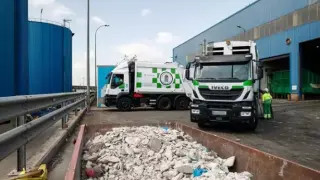 Un contenedor con escombros juntoa dos camiones de basura