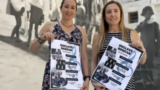 Beatriz Oliván y Laura Baquero con el cartel y en uno de los enclaves donde sonará la música, en la calle La Iglesia.
