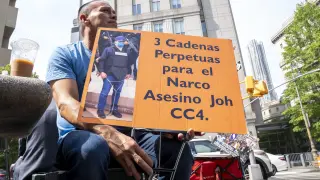 Un hombre sostiene una pancarta que pide "3 cadenas perpetuas al expresidente hondureño Juan Orlando Hernández" este miércoles, frente al tribunal federal de Manhattan en Nueva York