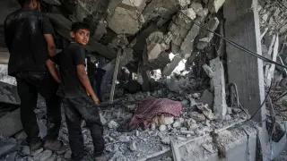 Palestinos entre escombros y cuerpos tras el ataque israelí en Al Nuseirat.