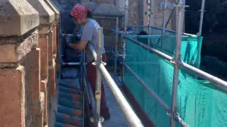 Una restauradora trabaja en la limpieza de un muro de la escalinata.