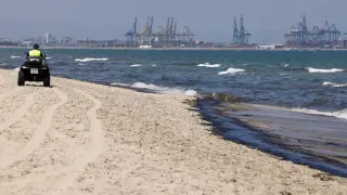 Un agente de la Policía Local recorre la playa afectada por el vertido de combustible, que según las primeras estimaciones mide entre 1,5 y dos kilómetros, y que ha obligado a prohibir el baño en las playas de l'Arbre del Gos y El Saler, en Valencia,
