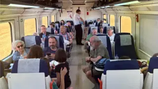 El revisor reparte agua a los viajeros del tren regional Huesca-Canfranc